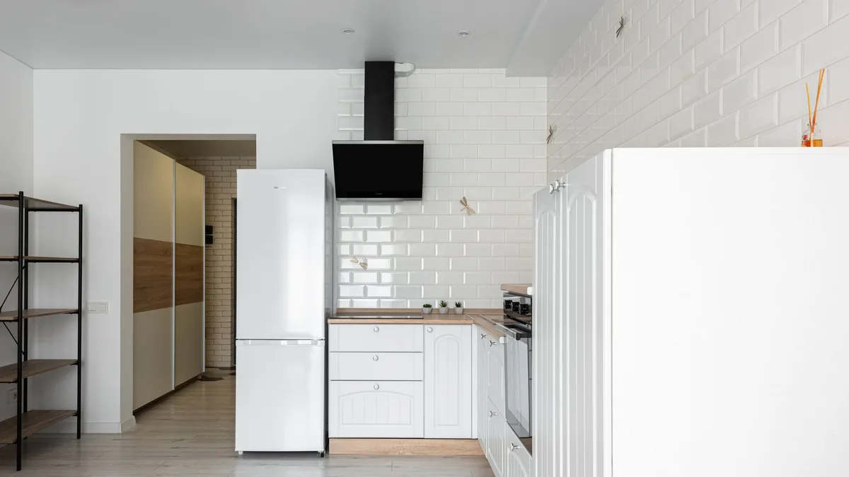 Frigorifico blanco integrado en una cocina luminosa de pared de ladrillo pintado