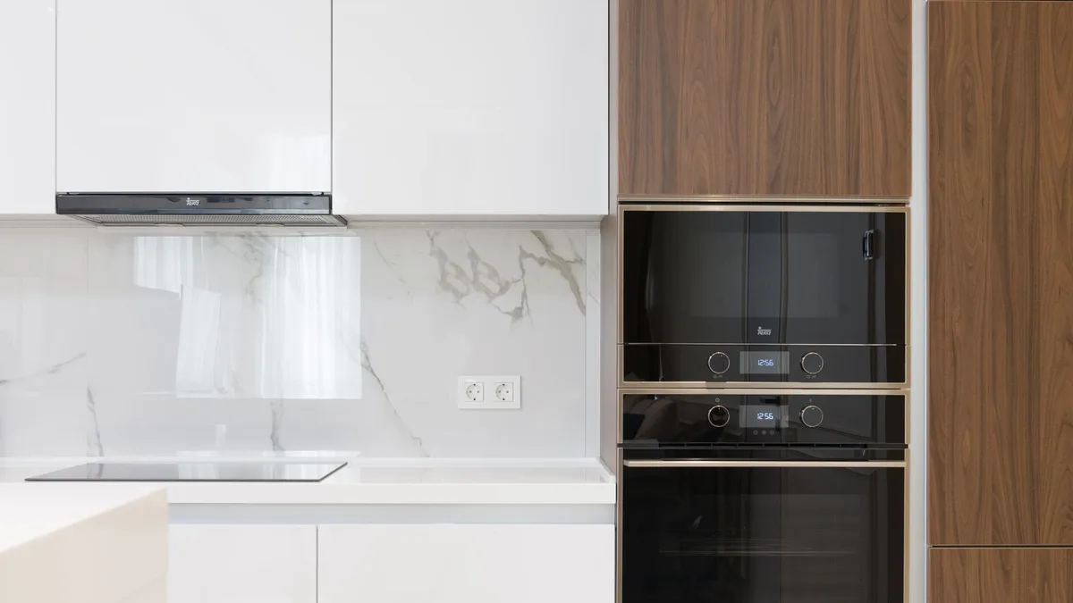 Cocina moderna blanca con horno y microondas integrados en una columna