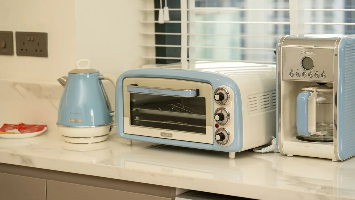 Hervidor, minihorno y cafetera de goteo de estilo retro sobre una encimera de mármol