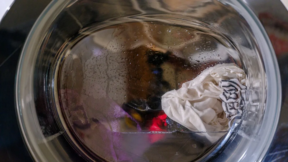 Agua estancada en el fondo del tambor de una lavadora con la puerta abierta
